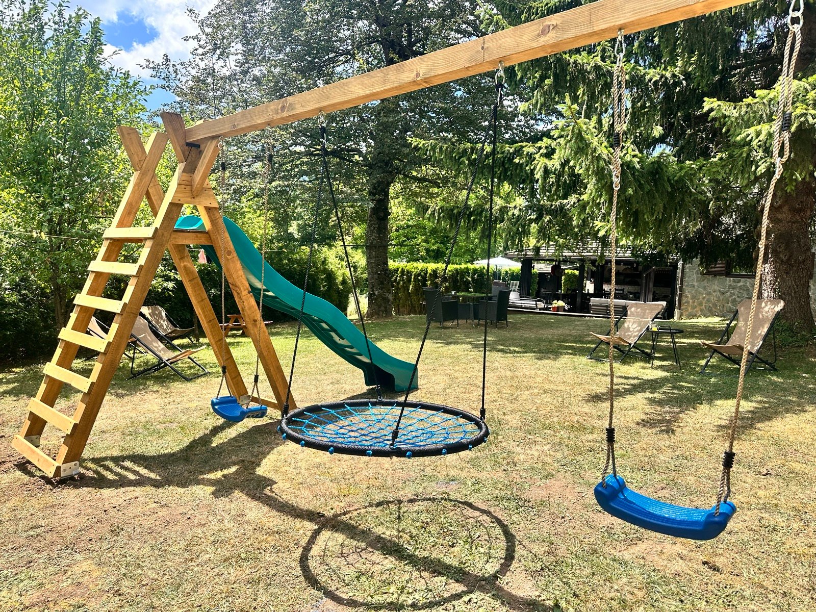 Kinderspielplatz mit Schaukeln und Rutsche im Garten der Villa Mukinja